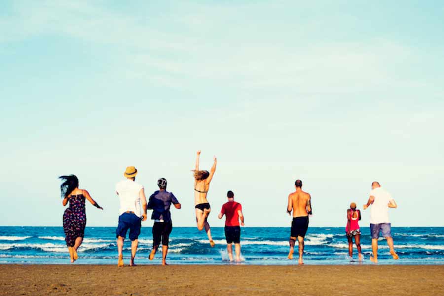 diverse-group-friends-running-beach